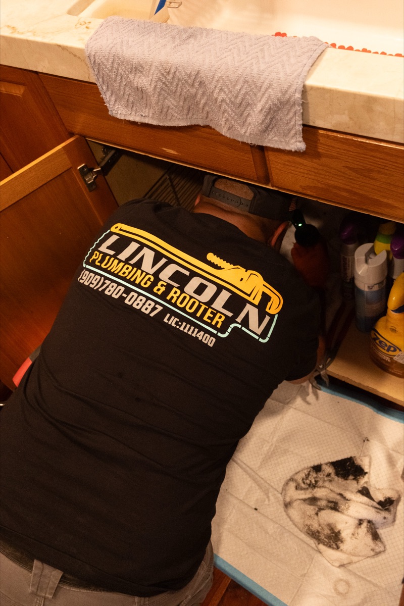 Lincoln Plumbing & Rooter branded uniform on a technician at work