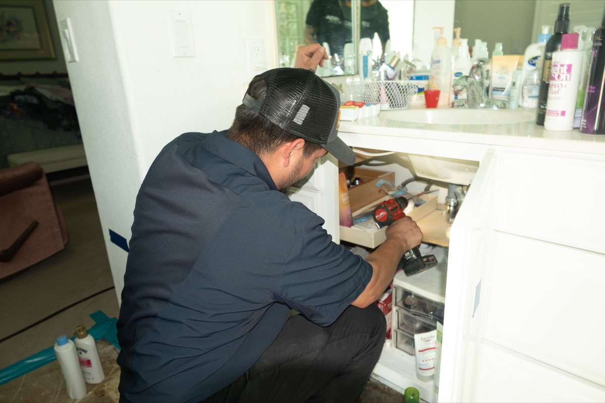 Technician installing a fixture under a bathroom sink