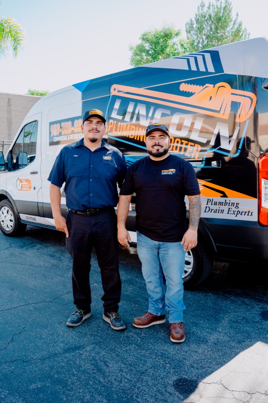 Two Lincoln Plumbing & Rooter technicians standing in front of a company van