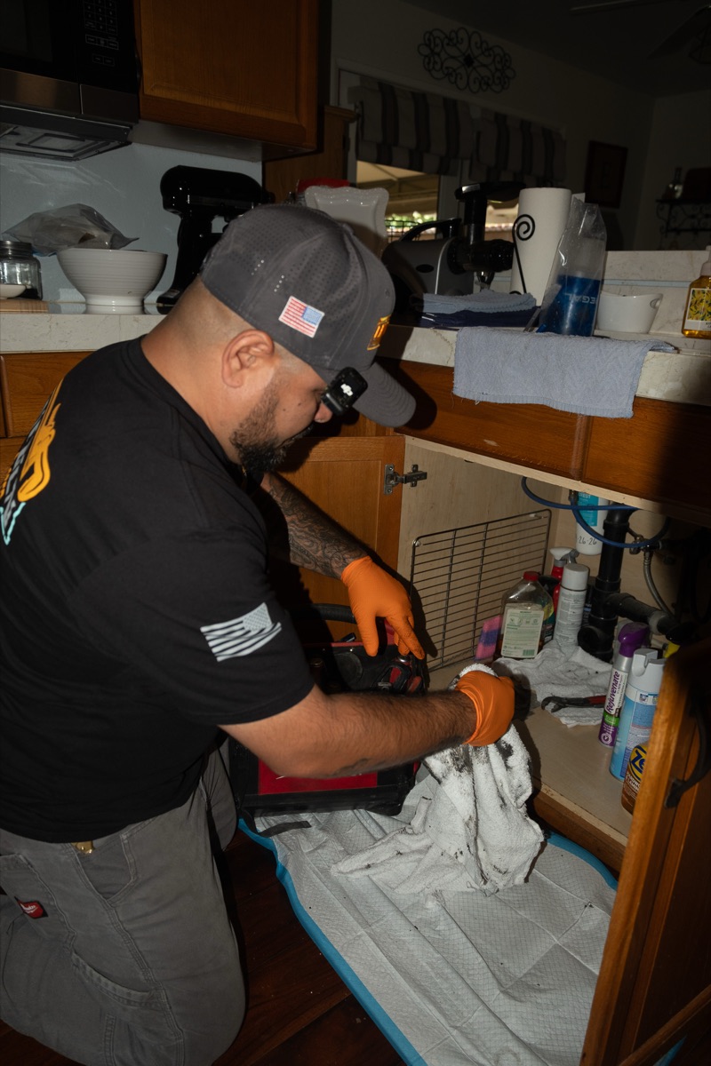 Technician repairing a kitchen sink at night